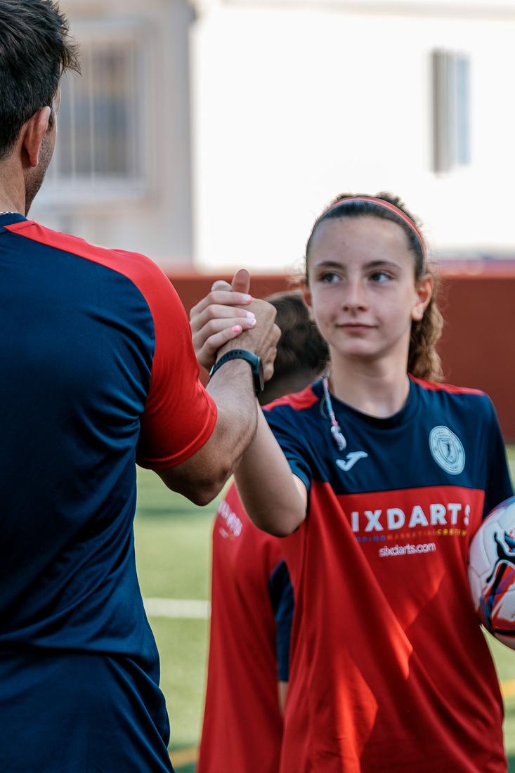 Una jugadora saluda al entrenador al empezar la sesión